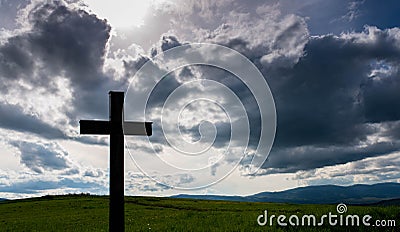 Simple wooden catholic cross silhouette, dramatic storm clouds Stock Photo