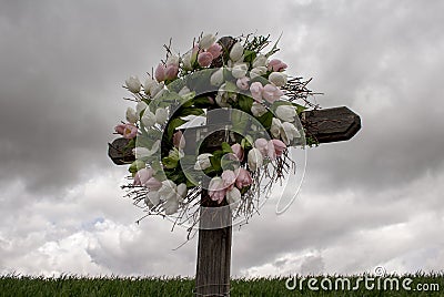 Simple Wooden Cross with a Wreath of White and Pink Silk Tulips Stock Photo