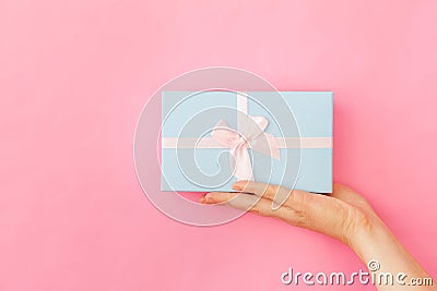 Simply design female woman hand holding blue gift box isolated on pink pastel colorful trendy background Stock Photo