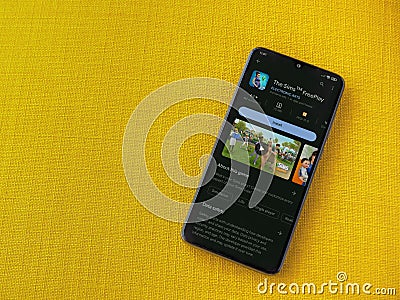 The Sims FreePlay app play store page on smartphone on a yellow fabric background Editorial Stock Photo