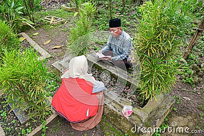 A mother and father and one son are reading the holy Koran to pray for someone who has died Editorial Stock Photo