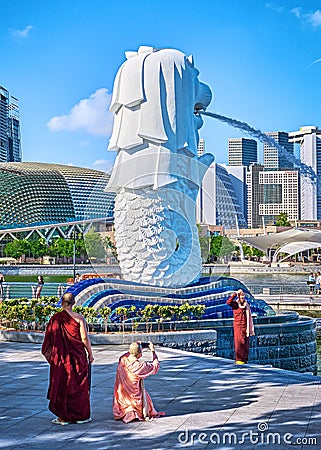 Singapore - Feb 25, 2020. Buddhist monks and nuns take pictures by famous Merlion fountain, symbol of Singapore, half Editorial Stock Photo