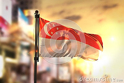 Singapore Flag Against City Blurred Background At Sunrise Backlight Stock Photo