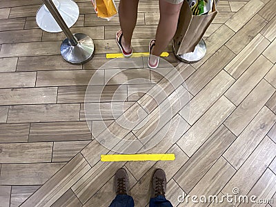 Queueing while maintaining social safe distancing measure in malls. Marked taped spots allocated for queueing; to maintain Editorial Stock Photo