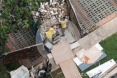 Singapore May2021 Workers unloading heaps of debris and construction waste from renovation of HDB flat into metal container for Editorial Stock Photo