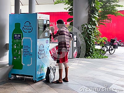 Singapore Sep2020 Man recycling plastic bottle in a reverse vending machine. Earn while recycling empty cans, plastic bottles; Editorial Stock Photo