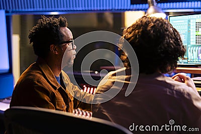 Singer and audio expert collaborating on mixing songs and creating new tracks Stock Photo