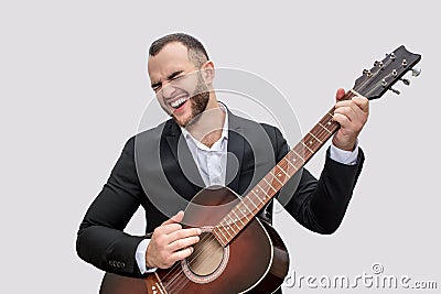 Singer in black suit stand and play on guitar. He sing song. Young man wears suit. Isolated on white background. Stock Photo