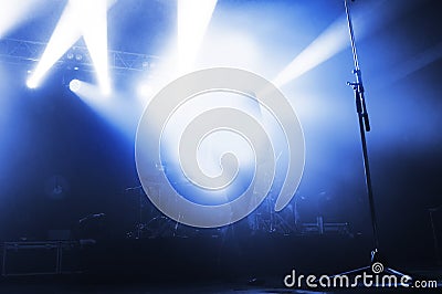 singer in the blue light of spotlights on the stage of a music festival. the concert lead goes to the microphone. Stock Photo