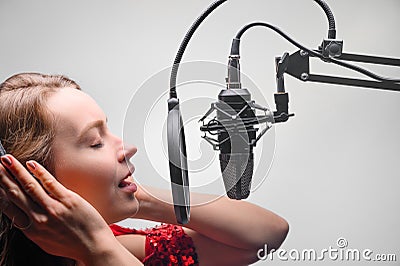 Singer or radio host working in a recording studio with a microphone in headphones close-up, blogging, radio, recording an album Stock Photo