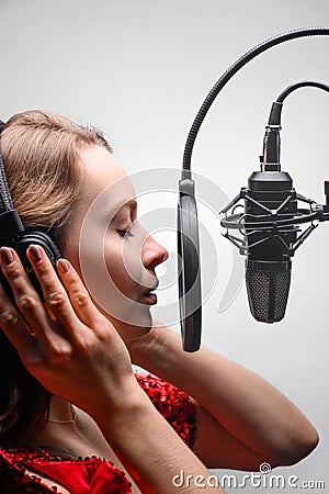 Singer or radio host working in a recording studio with a microphone in headphones close-up, blogging, radio, recording an album Stock Photo