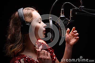 A singer or radio host is working in a recording studio with a microphone in headphones close-up, blogging, radio, recording an Stock Photo