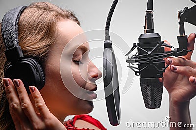 Singer or radio host working in a recording studio with a microphone in headphones close-up, blogging, radio, recording an album Stock Photo