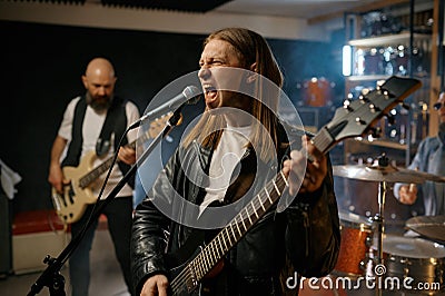 Singer singing in microphone playing guitar, repetition of rock band in garage Stock Photo