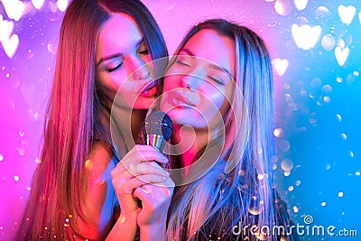 Singing Women with Microphone, party, Karaoke bar. Beauty Glamour girl friends singing and dancing on Stage. Rock singers Stock Photo