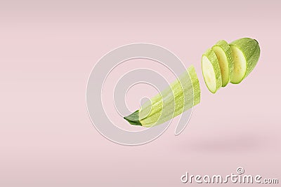 Singl vegetable marrow raw fresh sliced several parts small flying on pink background. Stock Photo