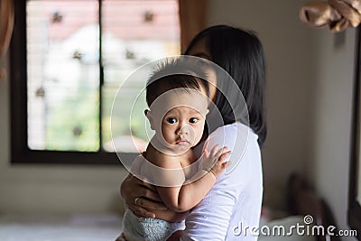 Single asian mother carrying baby cute boy in bedroom,Mother`s day concept Stock Photo