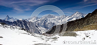 Single backcountry skier in a vast mountain landscape on his way down from a high summit with a great view of the Matterhorn and s Stock Photo