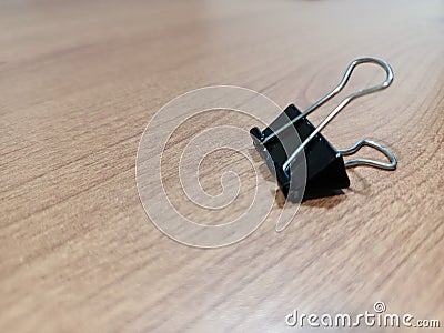 Single binder paper clip on wooden table Stock Photo