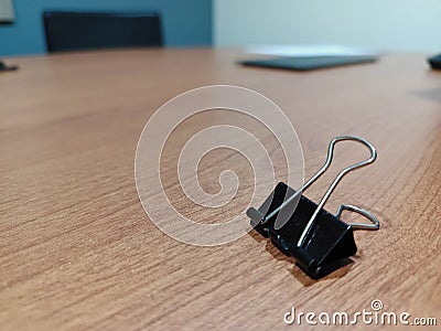 Single binder paper clip on wooden table Stock Photo