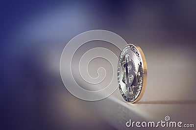 Single bitcoin standing on the edge of the table Stock Photo