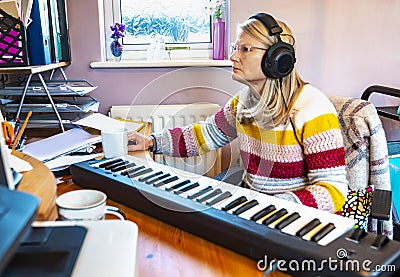 Single,blonde housewife and professiional musician working from home, using midi keyboard with recording software,England,United Stock Photo