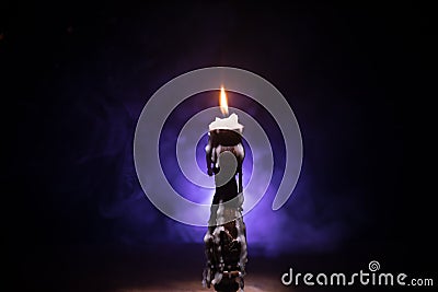 Single burning candle. Light of flame and flowing candle wax, dark background Stock Photo