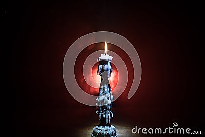 Single burning candle. Light of flame and flowing candle wax, dark background Stock Photo