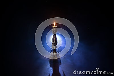 Single burning candle. Light of flame and flowing candle wax, dark background Stock Photo