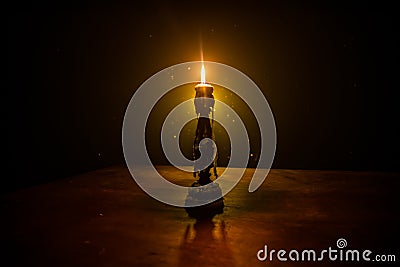 Single burning candle. Light of flame and flowing candle wax, dark background Stock Photo