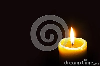 Single Burning Yellow Candle Glowing on a Dark Background. Copy Space Stock Photo