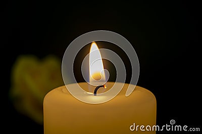 Close up of burning yellow wax candle and rose Stock Photo