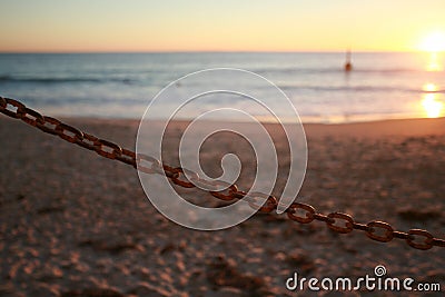 Single chain link against an out of focus beach sunset in the background Stock Photo