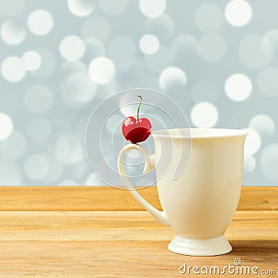 Single cherry on cup handle on bokeh background Stock Photo