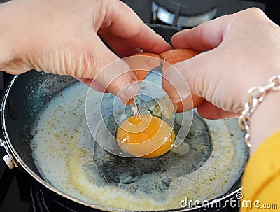 Single cracked egg poured onto a pan in the kitchen Stock Photo