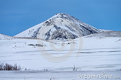 Single dramatic symetrical volcanic,snow covered cone near lake Myvatn, Iceland Stock Photo