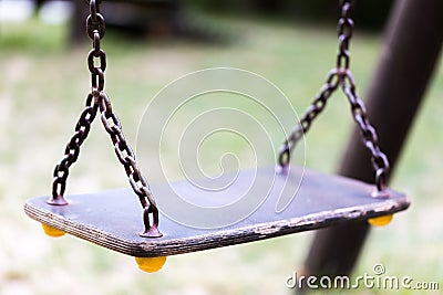 Single empty old swing on metal chain in child playground close Stock Photo