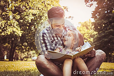 Single father sitting on grass with little daughter. Stock Photo