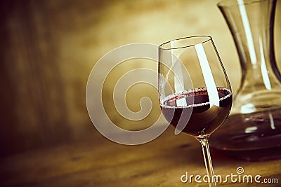 Single glass of red wine alongside a decanter Stock Photo