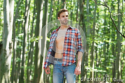 Single handsome guy with sexy bare torso in open shirt casual style stand in woods on sunny summer day natural landscape Stock Photo