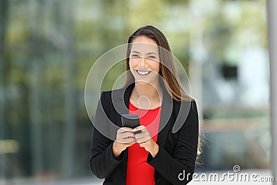Happy executive holding phone looking at you Stock Photo