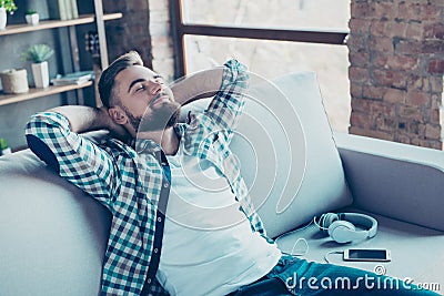 Single, happy young man in checkered shirt is relaxing on the so Stock Photo