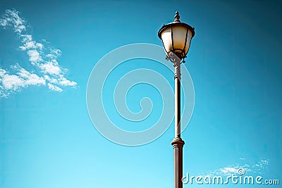 single lamp post lamp on thin pole against light blue sky Stock Photo