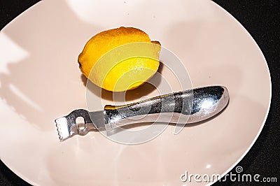 Single lemon with lemon zester, on round, white plate Stock Photo