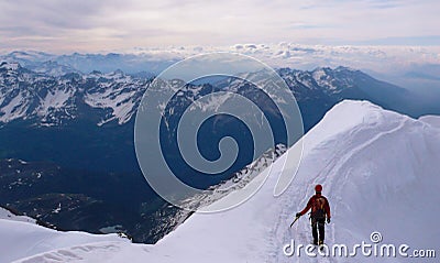 Single male mountain climber in red on a narrow snow ridge Stock Photo