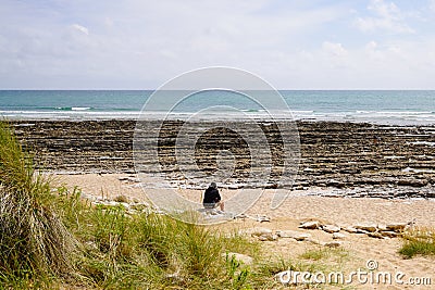 Single man sitting rocks on sand beach in behind rear view Stock Photo