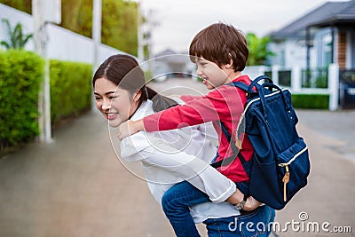 Single mom carrying and playing with her children near home with villa street background. People and Lifestyles concept. Happy Stock Photo