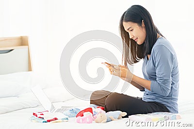 Single mom start working day on a laptop sitting on the bed in the morning. Working from home concept, shopping online Stock Photo