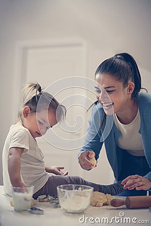 Single mother and little girl together in kitchen baking cookie. Stock Photo