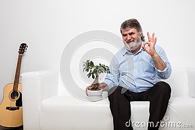 Single old men on white couch with a bonsai Stock Photo